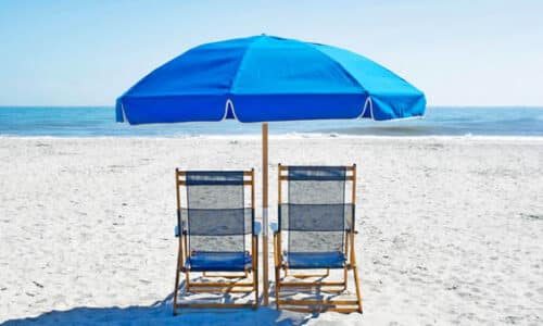 two beach chairs sitting under a bright blue umbrella on a white sand beach looking at the ocean at the Westin Hilton Head, SC