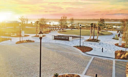 Bright yellow sunset over a town courtyard with street lamps and sand and green spaces